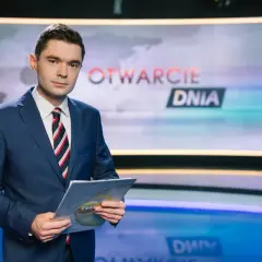 Jan Niedziałek, prezenter "Otwarcie Dnia", w garniturze trzyma dokumenty. Jego życiorys to historia kariery w mediach.