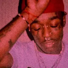 Lil Uzi Vert z diamentem na czole, w czerwonej czapce i z biżuterią.