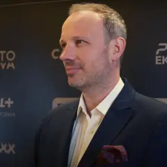 Marcin Majewski z TVN w eleganckim garniturze, na tle logotypów PGE Ekstraklasa i Canal+.