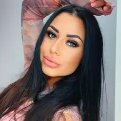 Stella z Love Island, z długimi czarnymi włosami i wyrazistym makijażem, pozuje do zdjęcia.
