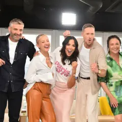 Uśmiechnięci dziennikarze i prezenterzy TVN pozują do zdjęcia, świętując sukces.