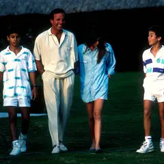 Julio Iglesias z dziećmi, dwoma synami i córką, spacerują po trawniku w letnich strojach.