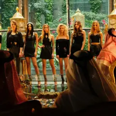 Scena z afery dubajskiej: kobiety w czarnych strojach prezentują się przed mężczyznami w tradycyjnych arabskich strojach.