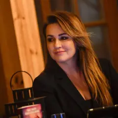 Beata Tadla, wiek nieznany, w czarnej marynarce, z długimi, brązowymi włosami, uśmiecha się lekko.