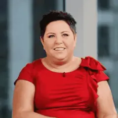 Uśmiechnięta Dorota Wellman w czerwonej sukience. Jej wiek nie jest widoczny, ale emanuje pewnością siebie.