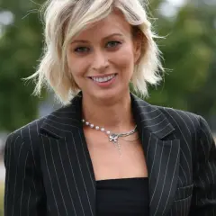 Uśmiechnięta Katarzyna Zdanowicz, której wiek dodaje jej uroku, w eleganckiej marynarce w paski i naszyjniku z pereł.