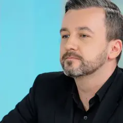 Krzysztof Skórzyński, znany dziennikarz, w czarnym garniturze. Ile ma lat? Trudno zgadnąć, ale wygląda na około 40.
