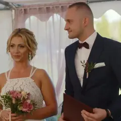 Iza i Kamil, ślub od pierwszego wejrzenia. Panna młoda z bukietem, pan młody w garniturze, patrzą na siebie z uśmiechem.