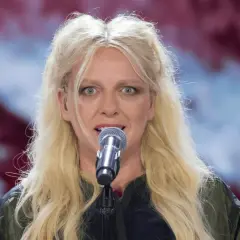 Ania Wyszkoni śpiewa do mikrofonu. Ciekawe, ile lat ma Ania Wyszkoni, gdy patrzymy na jej energię na scenie.