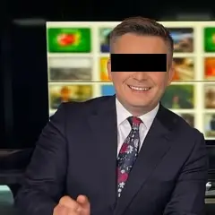 Uśmiechnięty mężczyzna w garniturze, z zasłoniętymi oczami, siedzi przed ekranami w studiu TVN. To Mateusz Walczak.