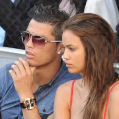 Irina Shayk i Ronaldo, w okularach przeciwsłonecznych i z zegarkiem, siedzą obok siebie, wyglądając na zamyślonych.