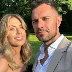 Aleksandra Gryś z mężem na tle ogrodu. Uśmiechnięta para pozuje do zdjęcia w słoneczny dzień.