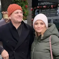 Bartłomiej Topa z żoną w zimowej stylizacji, uśmiechnięci na tle świątecznych dekoracji.