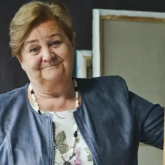Uśmiechnięta Aleksandra Piotrowska, psycholog, opiera się o drewniane krzesło. Jej wiek jest tajemnicą, ale doświadczenie widać w oczach.