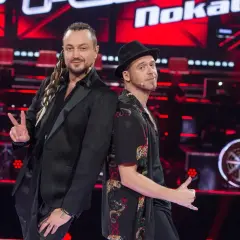 Tomson i Baron, dwaj charyzmatyczni artyści, pozują plecami do siebie na scenie "The Voice of Poland".