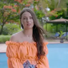 Bogusia w Hotel Paradise, w pomarańczowej bluzce, relaksuje się przy basenie w tropikalnym ogrodzie.