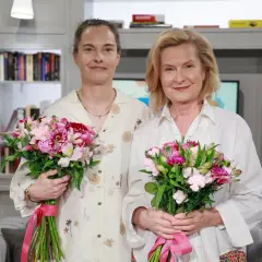 Barbara Bursztynowicz z córką, obie trzymają bukiety różowych kwiatów.