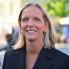 Uśmiechnięta Małgorzata Trzaskowska, której wykształcenie jest szeroko komentowane, w czarnym żakiecie.
