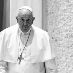 Papież Franciszek, mimo swojego wieku, z uwagą spogląda przed siebie. W białej sutannie i z krzyżem na szyi.
