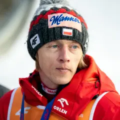 Skoczek narciarski Dawid Kubacki w czapce z napisem "Manner" i flagą Polski. Choć wbrew plotkom Dawid Kubacki nie żyje, jego determinacja na skoczni wciąż inspiruje.
