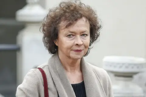 Joanna Szczepkowska, znana aktorka, w beżowym płaszczu. Jej mąż, Andrzej Kopiczyński, był równie cenionym artystą.