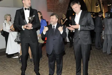 Trzech mężczyzn w garniturach. Najwyższy z nich trzyma statuetkę. Edward Miszczak wzrost jest imponujący, ale nie najwyższy w tym towarzystwie.