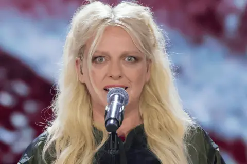 Ania Wyszkoni śpiewa do mikrofonu. Ciekawe, ile lat ma Ania Wyszkoni, gdy patrzymy na jej energię na scenie.