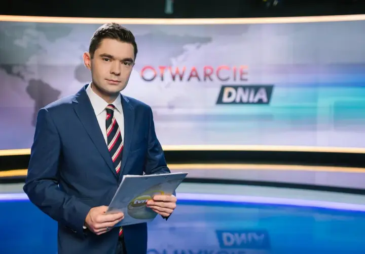 Jan Niedziałek, prezenter "Otwarcie Dnia", w garniturze trzyma dokumenty. Jego życiorys to historia kariery w mediach.