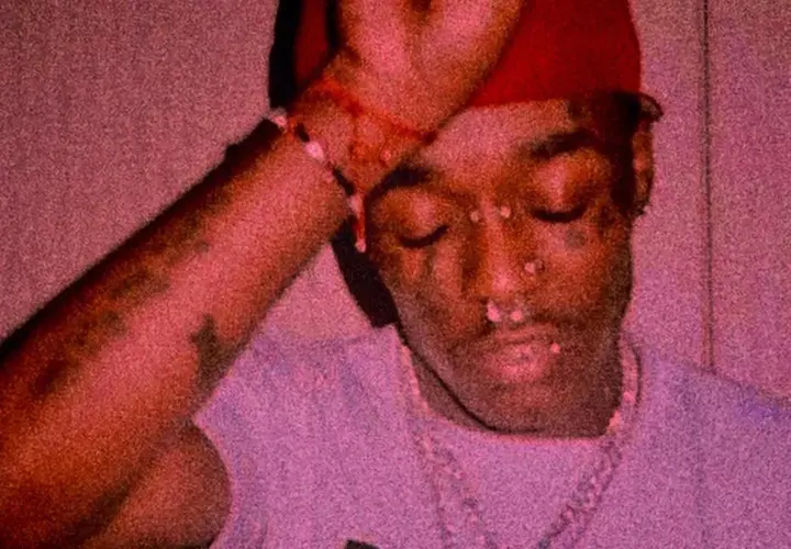 Lil Uzi Vert z diamentem na czole, w czerwonej czapce i z biżuterią.