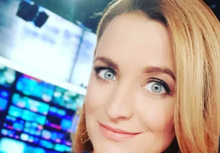 Dagmara Kaczmarek Szalkow z TVN Fakty z błękitnymi oczami i blond włosami, w tle ekrany.