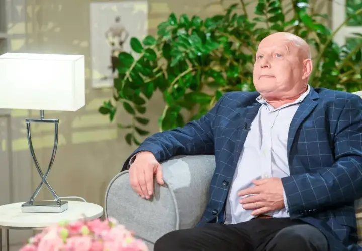 Krzysztof Jackowski w okryciu w kratę, oparty o sofę, jakby snuł najnowsze przepowiednie.