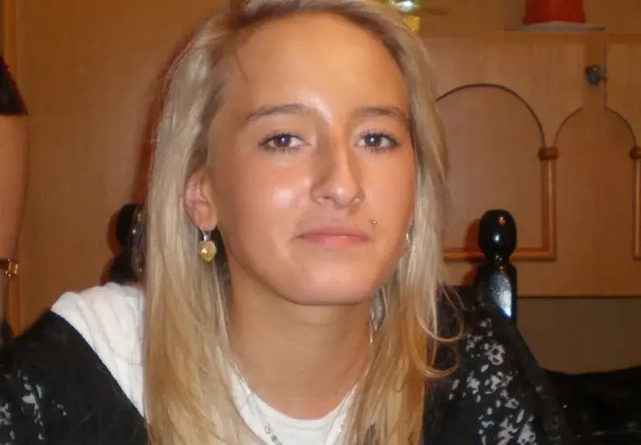 Młoda kobieta z blond włosami, kolczykiem w wardze i serduszkiem w uchu. Jej twarz jest w centrum uwagi, a w tle widać fragmenty mebli. Sprawa Iwony Wieczorek wciąż budzi emocje.