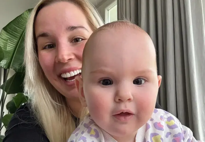 Uśmiechnięta blondynka z dzieckiem na rękach. Dziecko ma ok. 1 roku, a jego wiek to ile lat ma lil masti.