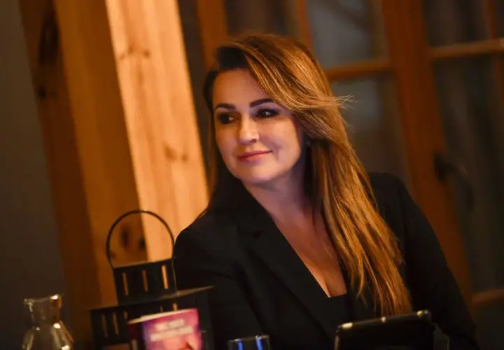 Beata Tadla, wiek nieznany, w czarnej marynarce, z długimi, brązowymi włosami, uśmiecha się lekko.