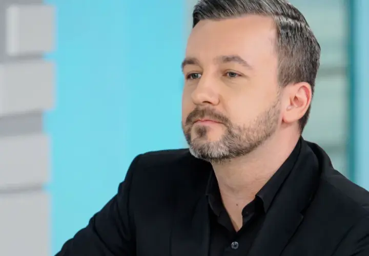 Krzysztof Skórzyński, znany dziennikarz, w czarnym garniturze. Ile ma lat? Trudno zgadnąć, ale wygląda na około 40.