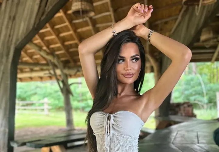 Ania Kokocińska, w wieku, w letniej stylizacji, pozuje pod drewnianą altaną.