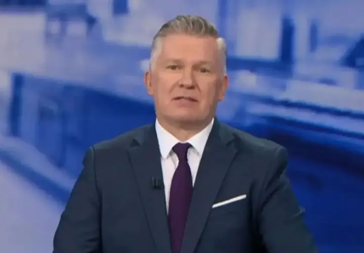 Mężczyzna w garniturze, prowadzący tvn wiadomości, z uwagą przekazuje informacje.