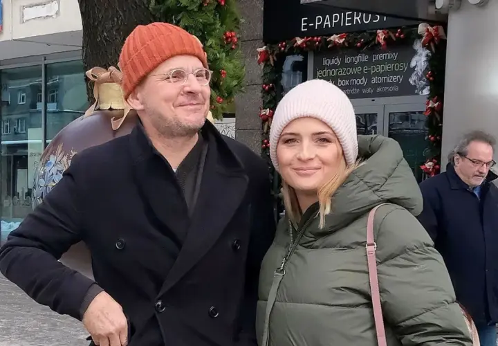 Bartłomiej Topa z żoną w zimowej stylizacji, uśmiechnięci na tle świątecznych dekoracji.