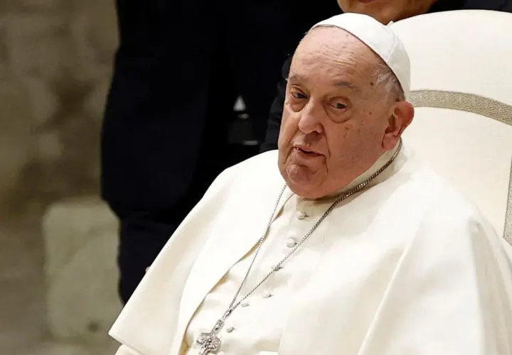 Papież Franciszek, siedzący na białym krześle, w białej sutannie i piusce. Jego wzrost jest typowy dla mężczyzny w jego wieku.
