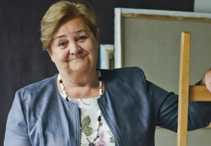 Uśmiechnięta Aleksandra Piotrowska, psycholog, opiera się o drewniane krzesło. Jej wiek jest tajemnicą, ale doświadczenie widać w oczach.