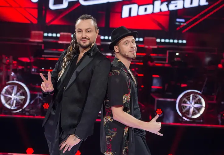 Tomson i Baron, dwaj charyzmatyczni artyści, pozują plecami do siebie na scenie "The Voice of Poland".