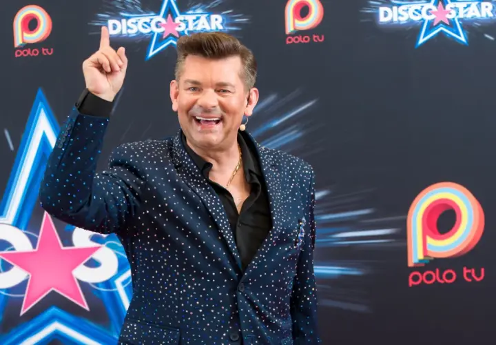 Uśmiechnięty Zenek Martyniuk w błyszczącej marynarce, pozuje na tle logo Polo TV. Ciekawe, ile lat ma Zenek Martyniuk?