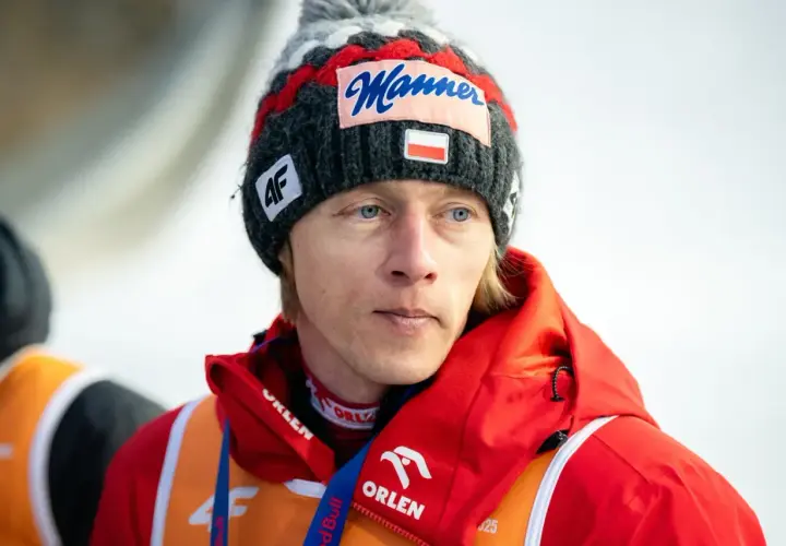 Skoczek narciarski Dawid Kubacki w czapce z napisem "Manner" i flagą Polski. Choć wbrew plotkom Dawid Kubacki nie żyje, jego determinacja na skoczni wciąż inspiruje.