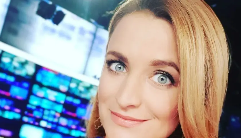 Dagmara Kaczmarek Szalkow z TVN Fakty z błękitnymi oczami i blond włosami, w tle ekrany.