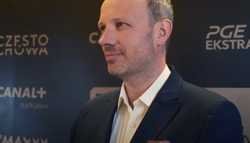 Marcin Majewski z TVN w eleganckim garniturze, na tle logotypów PGE Ekstraklasa i Canal+.