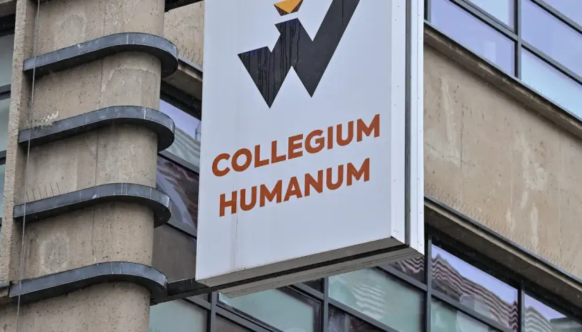 Tablica z napisem Collegium Humanum, budynek o surowej architekturze, w tle odbicia, które mogą sugerować aferę.