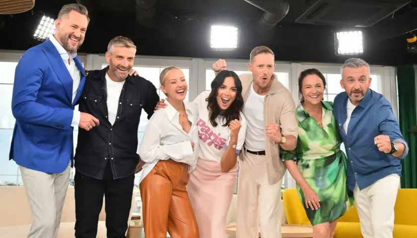 Uśmiechnięci dziennikarze i prezenterzy TVN pozują do zdjęcia, świętując sukces.