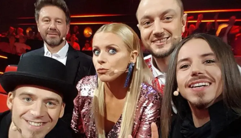 Uśmiechnięci jurorzy Voice of Poland w barwnych strojach, gotowi oceniać talenty.