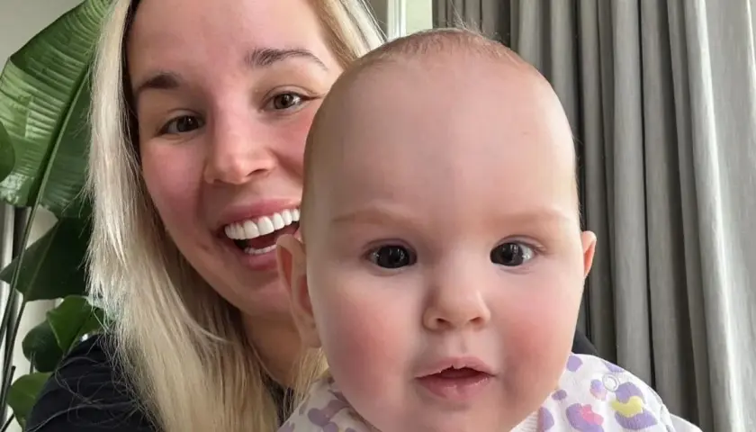 Uśmiechnięta blondynka z dzieckiem na rękach. Dziecko ma ok. 1 roku, a jego wiek to ile lat ma lil masti.