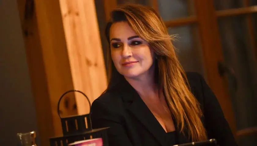 Beata Tadla, wiek nieznany, w czarnej marynarce, z długimi, brązowymi włosami, uśmiecha się lekko.